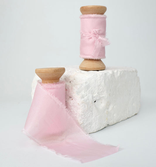 Two spools of baby pink 100% Habotai silk ribbon.